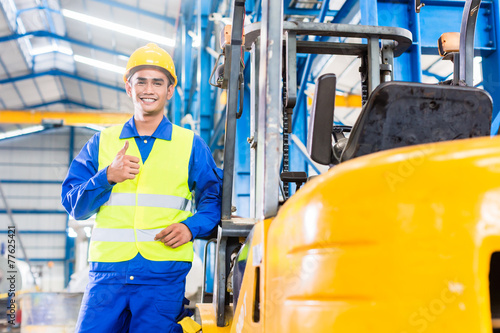 Forklift driver standing in manufacturing plant