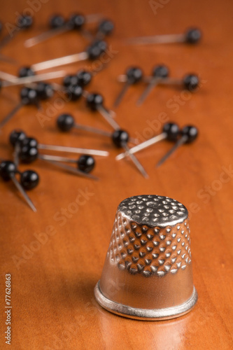 Thimble and needles on wooden table