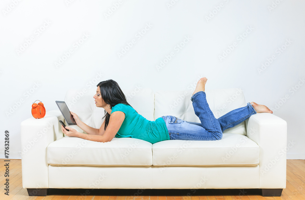 Young woman using electronic tablet sitting on sofa Young woman using electronic tablet sitting on sofa
