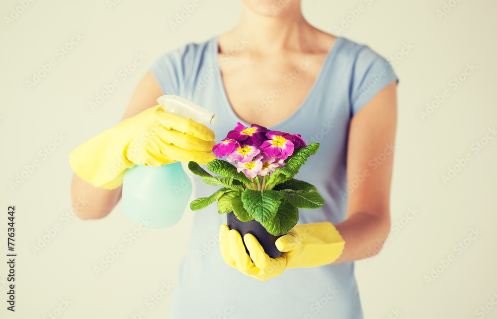 woman holding pot with flower and spray bottle