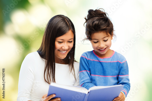 happy mother and little daughter reading book