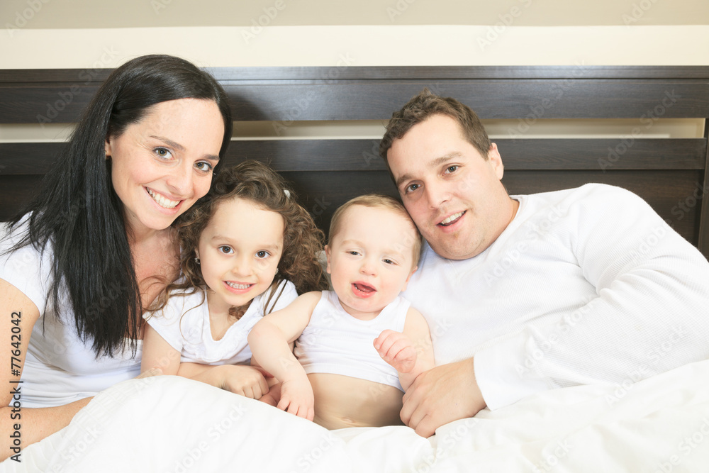 Young family resting together in parent's bed Young family resting together in parent's bed