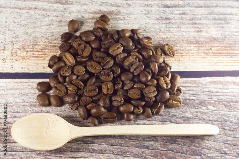 Black coffee and wooden spoon near coffee grains on vintage wooden background