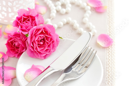 Romantic table setting with pink roses on a linen napkin
