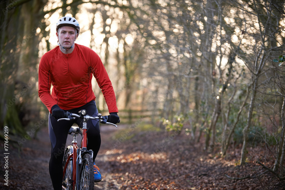Obraz premium Man Riding Mountain Bike Through Woodlands