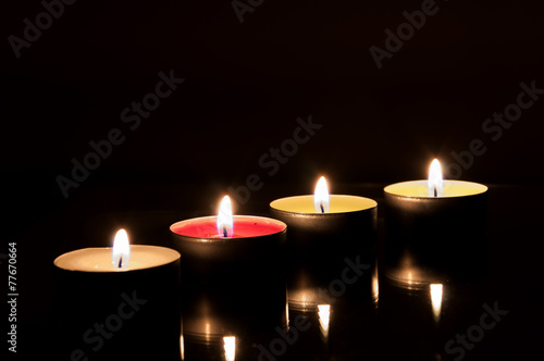 Four burning candles in the dark