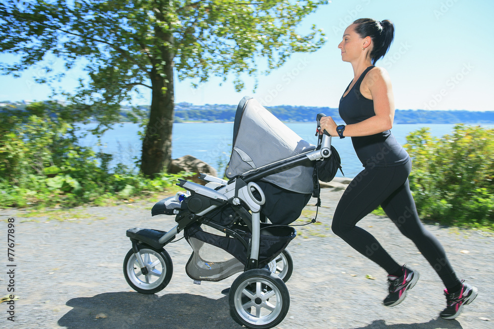 A Young mother jogging with a baby buggy A Young mother jogging with a baby buggy