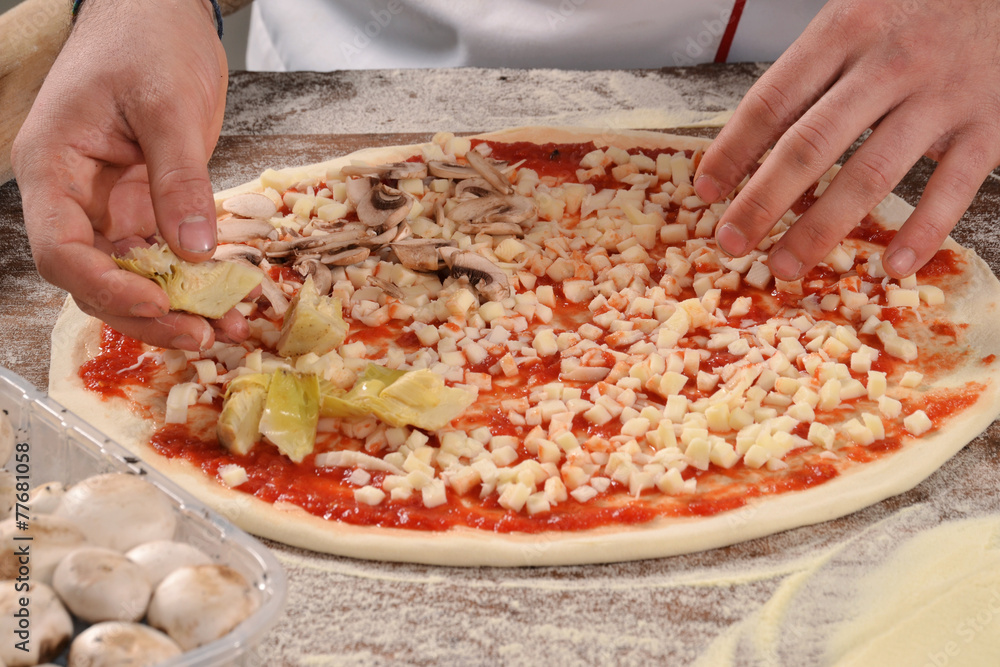 Manos preparando pizza.