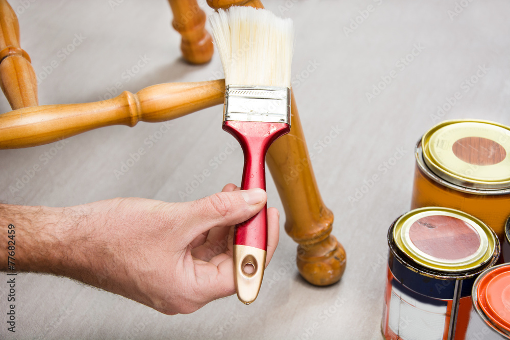 Man varnishing a chair with paintbrush