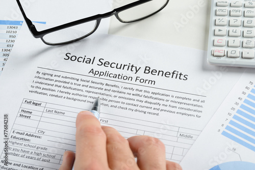 Photos Hand Holding Pen Over Social Security Benefits Form