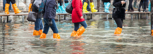 Photographie Close Up of legs with boots due to the high water in Venice.