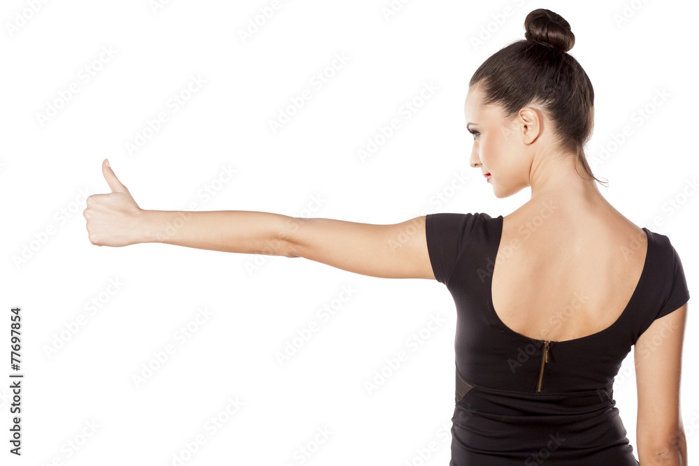 Back view of pretty young woman , showing thumb up Back view of pretty young woman , showing thumb up