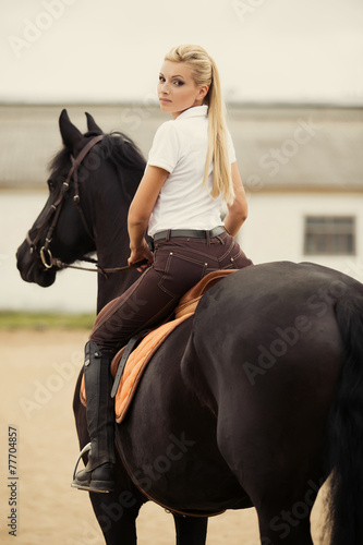 Image of happy female jockey on purebred horse outdoors