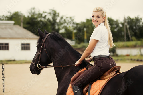 Image of happy female jockey on purebred horse outdoors