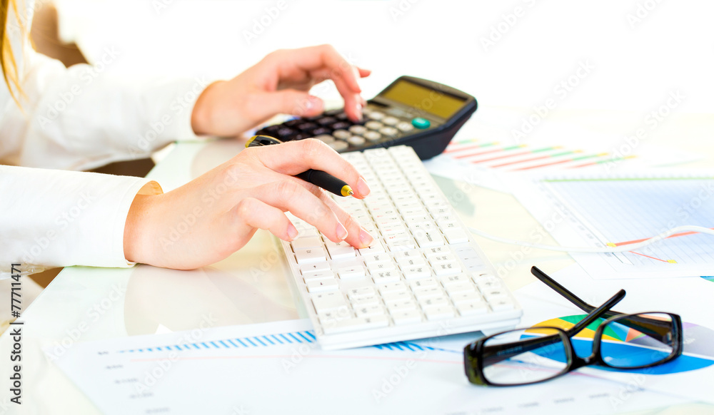 Fototapeta premium Woman with beautiful hands working on the calculator and keyboar
