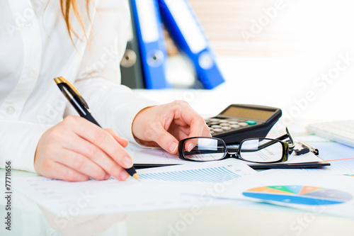 Woman at office desk signing a contract with shallow focus on si