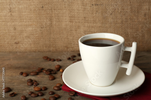 Cup of coffee with beans on rustic wooden background