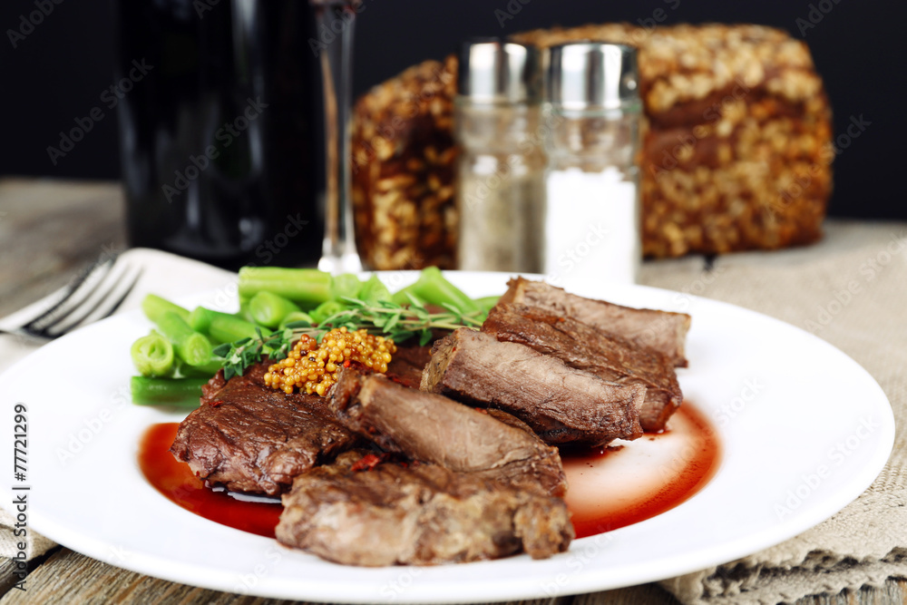 Steak on plate with bottle of wine on dark background Steak on plate with bottle of wine on dark background