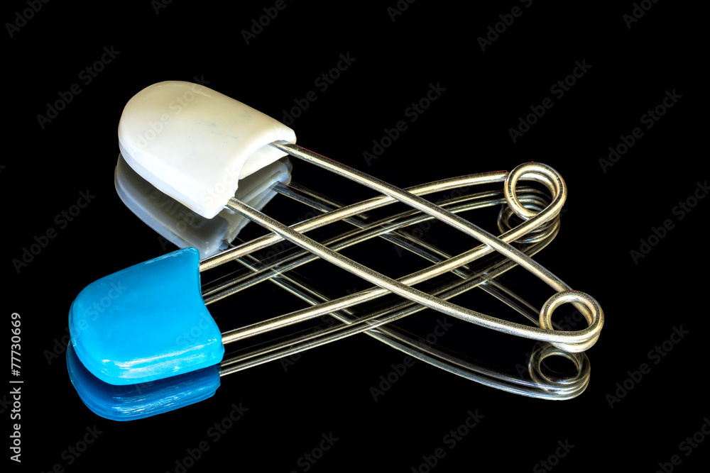 Baby diaper safety pins on a reflective surface Stock Photo