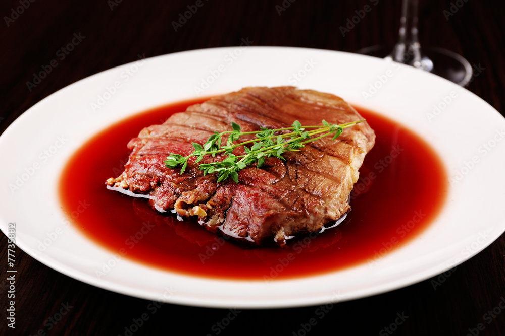 Grilled steak in wine sauce on plate on table close up Grilled steak in wine sauce on plate on table close up