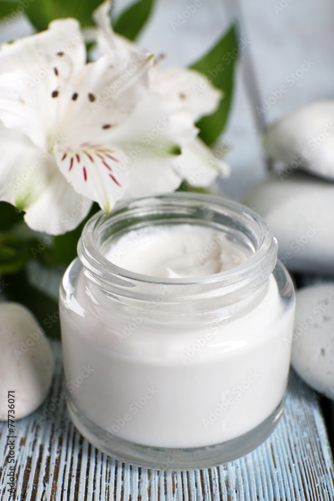 Cosmetic cream with flowers and spa stones on wooden background Cosmetic cream with flowers and spa stones on wooden background