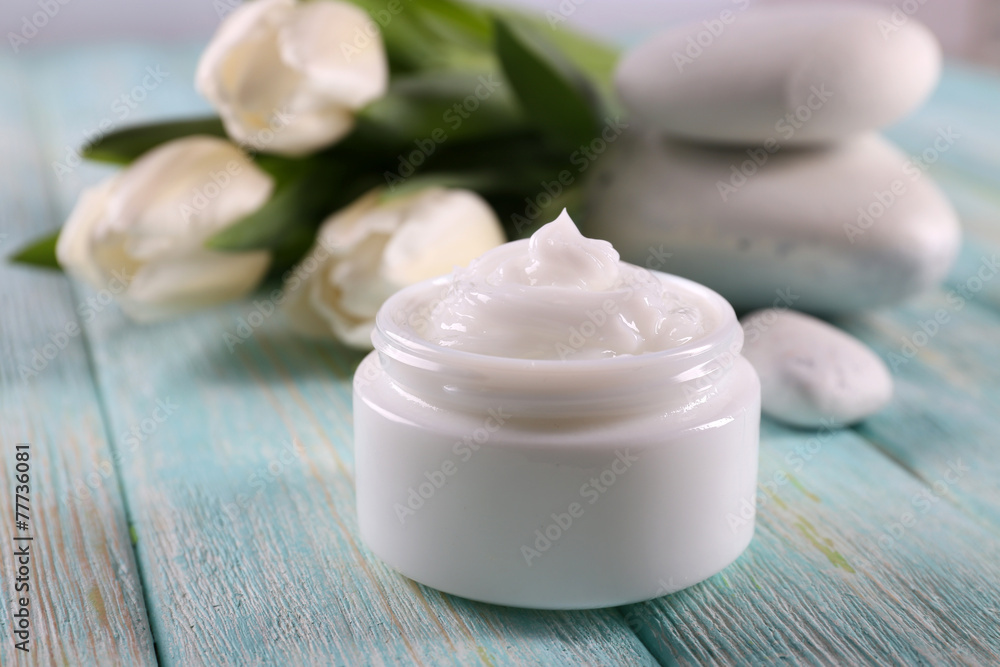 Cosmetic cream with flowers and spa stones on wooden background Cosmetic cream with flowers and spa stones on wooden background