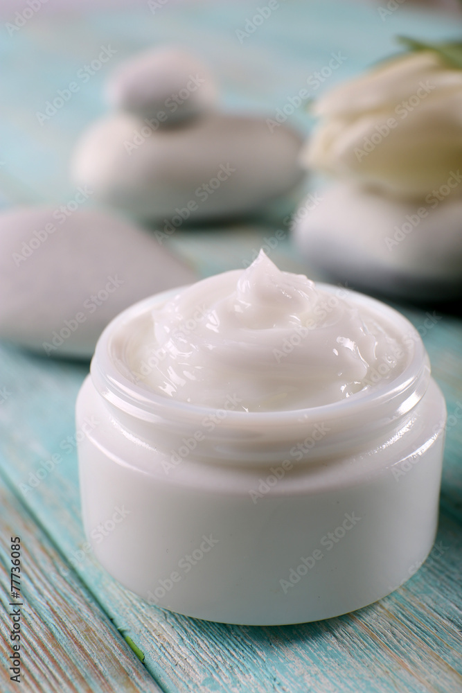Cosmetic cream with spa stones and tulip on wooden background Cosmetic cream with spa stones and tulip on wooden background