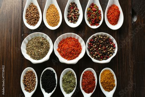 Different kinds of spices in bowls and spoons, close-up,