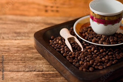 Cup with plate on tray full of coffee beans