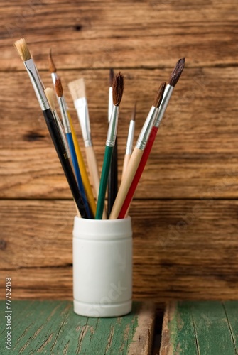 White jar with paintbrushes on green board