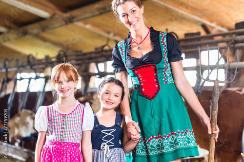 Bayrische Familie mit Milchkannen im Kuhstall