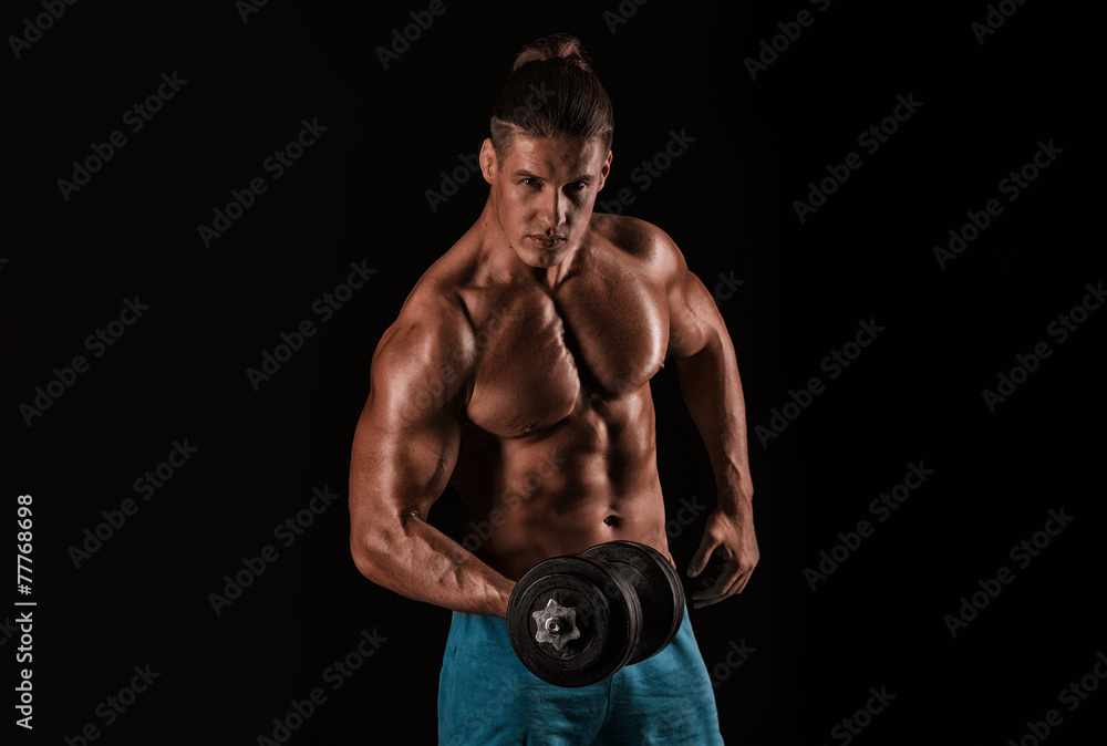 Strong athletic man with perfect body posing with dumbbells