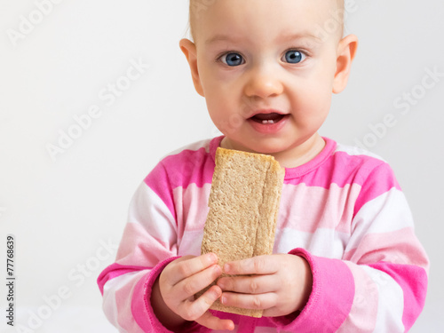 Infant eating  a slice of healthy  crunchy bread