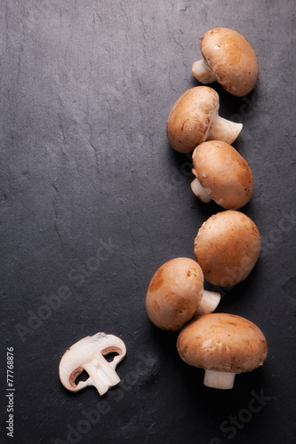 Sliced and whole Chestnut Mushrooms on background of dark slate.