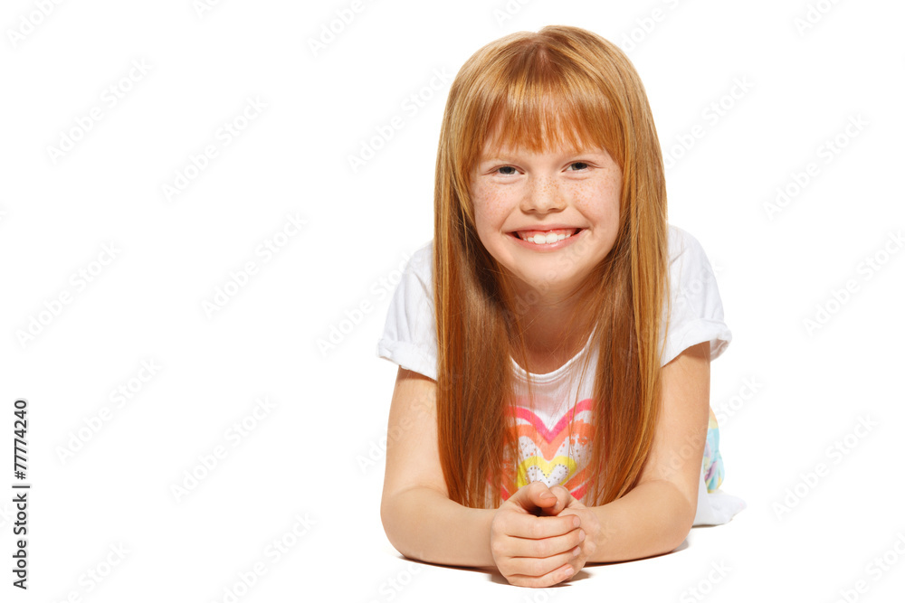 A cheerful little girl with red hair is lying; isolated A cheerful little girl with red hair is lying; isolated