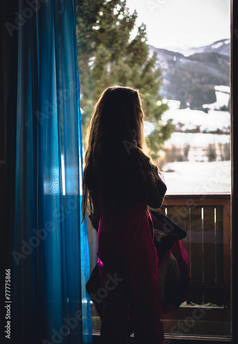 Toned shot of little girl looking on snowy forest through window