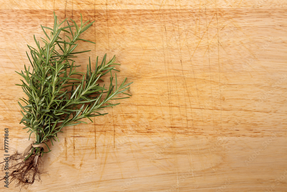 Bunch of fresh rosemary on an old wooden chopping board. Space f Bunch of fresh rosemary on an old wooden chopping board. Space f