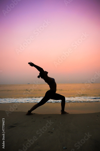 silhouette of woman practicing yoga on the beach sunrise