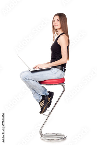Beautiful brunette woman sitting on a chair and holding a laptop