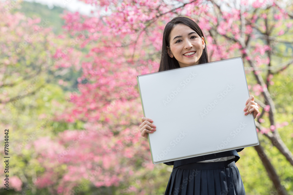 桜をバックにホワイトボードを持つ女子学生 桜をバックにホワイトボードを持つ女子学生