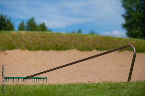 rake for golf laying on sand