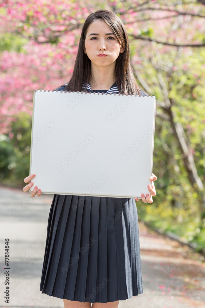 桜をバックにホワイトボードを持つ女子学生 桜をバックにホワイトボードを持つ女子学生