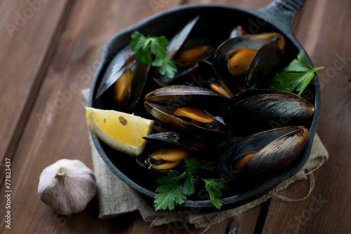 Boiled mussels with lemon, fresh parsley and garlic, close-up