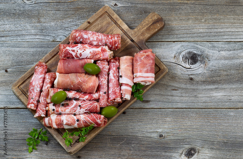 Various raw meats on rustic serving board