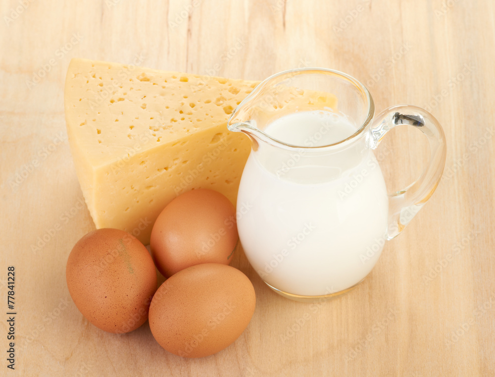 Big piece of cheese, glass jug with milk Big piece of cheese, glass jug with milk