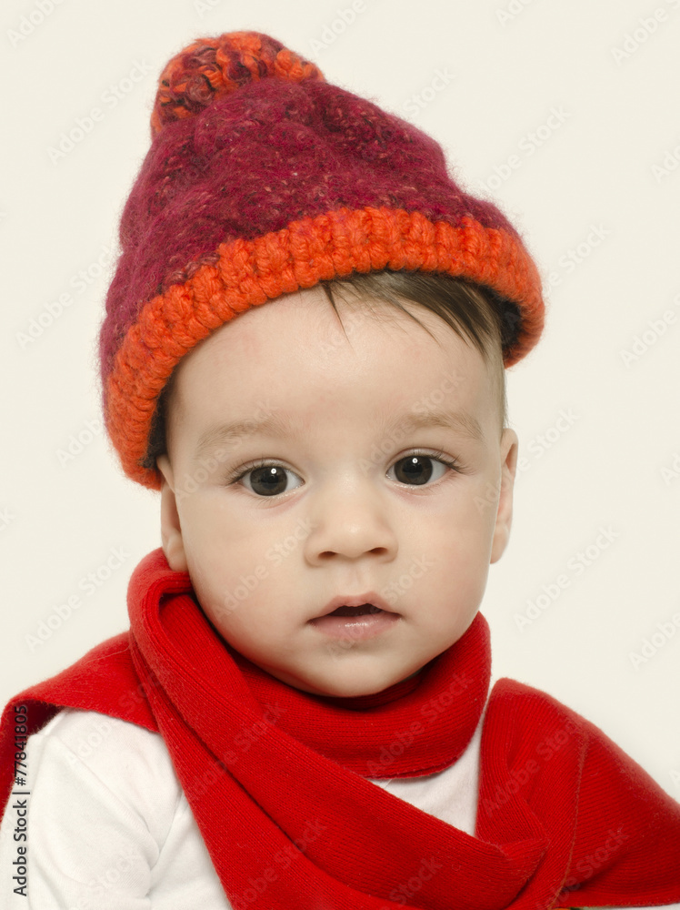 Innocent baby wearing a red hat and a muffler,looking adorable Innocent baby wearing a red hat and a muffler,looking adorable