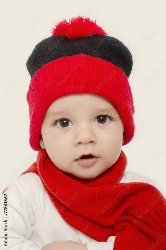 Innocent baby wearing a red hat and a muffler,looking adorable Innocent baby wearing a red hat and a muffler,looking adorable