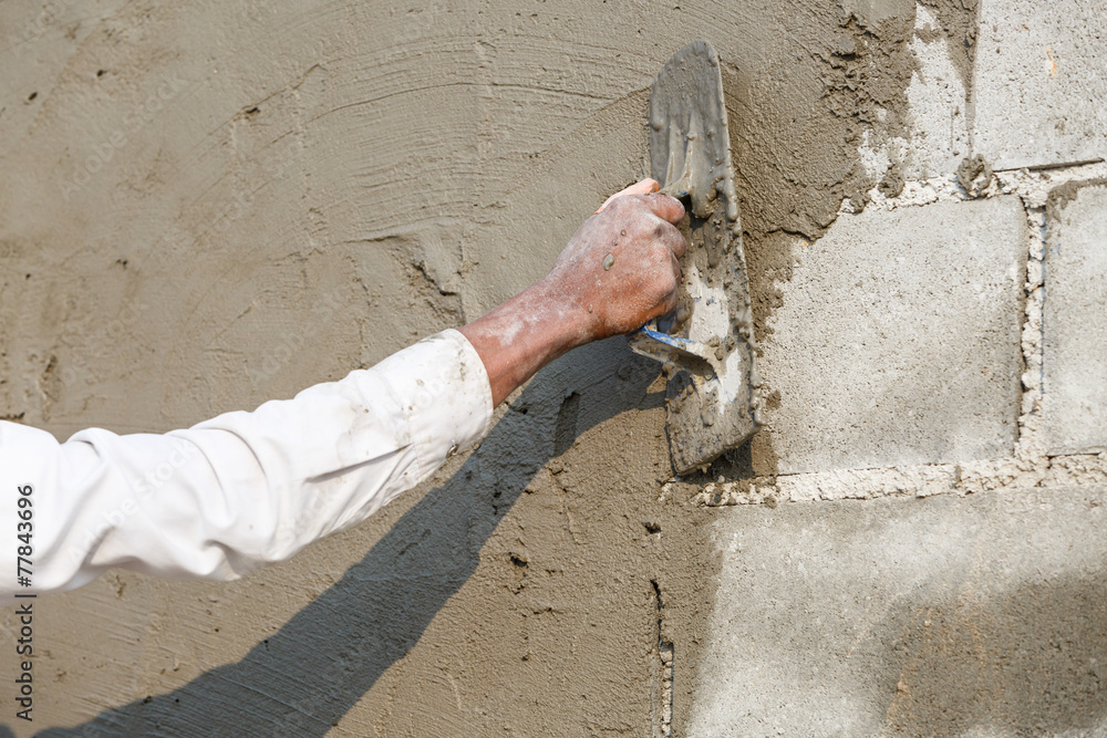 plasterer concrete worker at wall of house construction