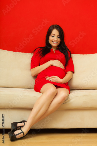 pregnant woman relaxing on sofa touching her belly