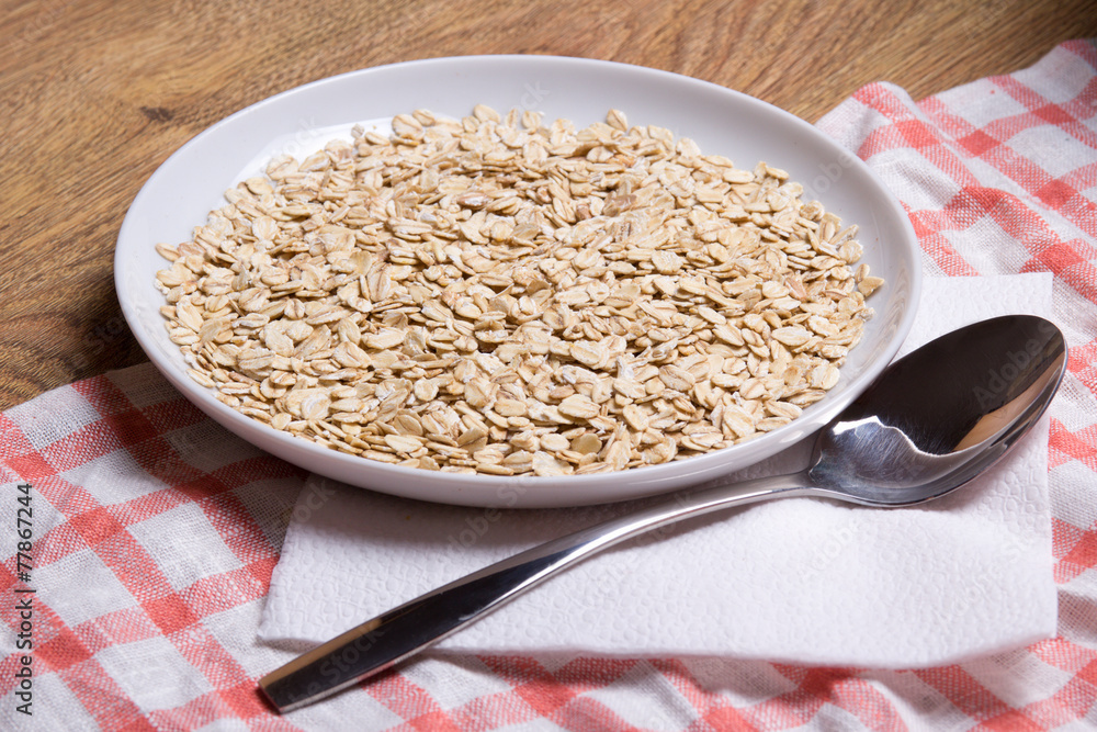 close up of oatmeal in plate with spoon on table close up of oatmeal in plate with spoon on table